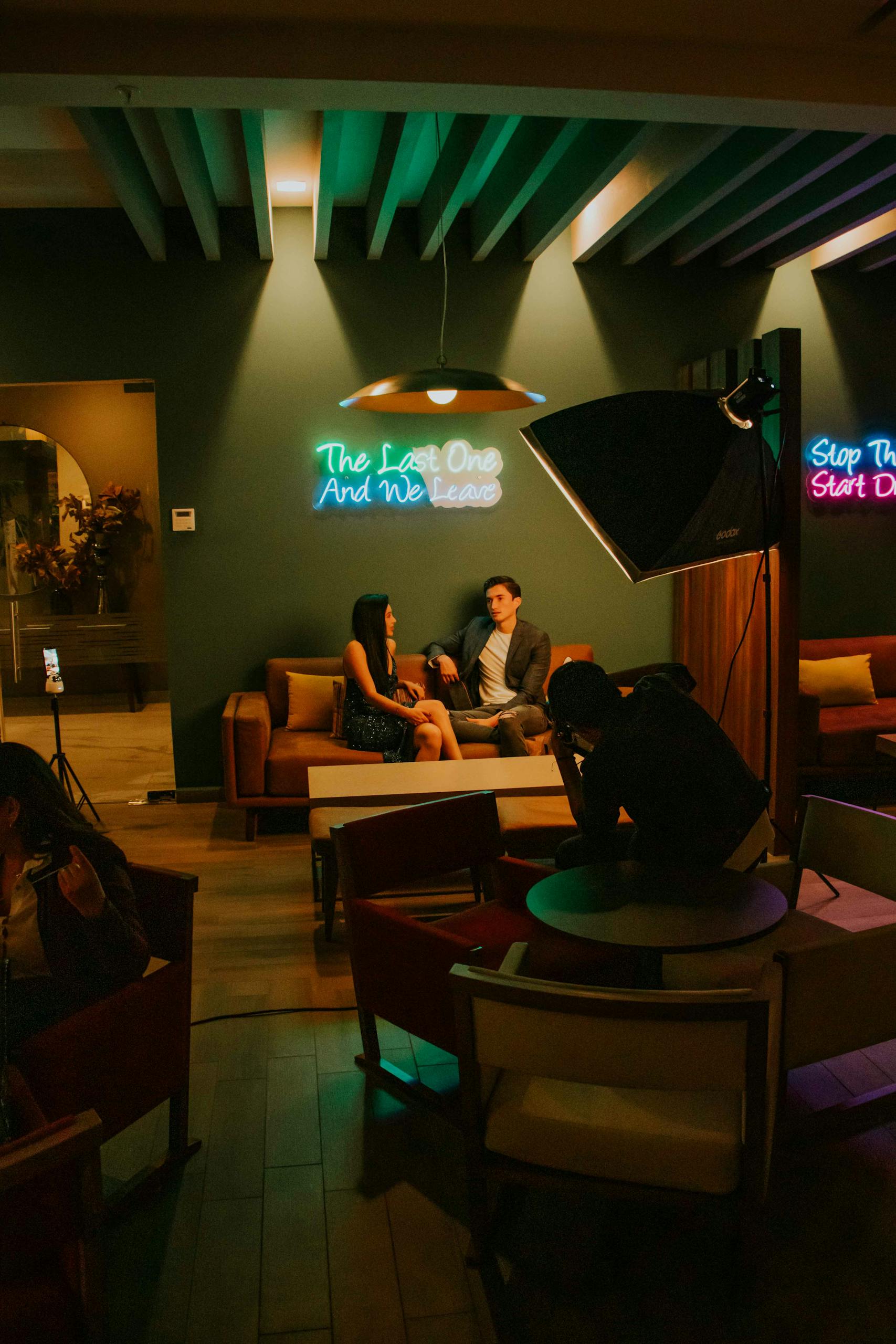 A couple sitting in a studio with neon lights, filmed by an operator with professional lighting.
